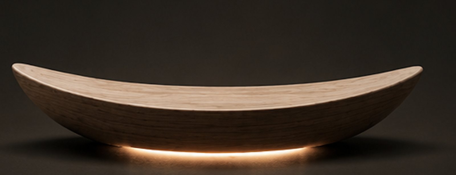 The wooden cradle in darkness with a soft light pooling beneath it